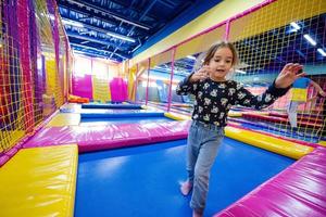 contento bambini giocando a interno giocare centro terreno di gioco. ragazza salto su trampolino. foto