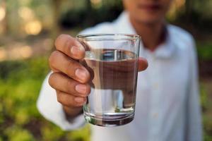 un' uomo detiene acqua per bere. dopo fatica a partire dal opera per Aiuto rilassare stanco. benefico acqua foto