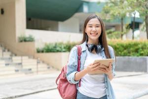 bellissimo alunno asiatico donna con zaino e libri all'aperto. Sorridi ragazza contento trasporto un' lotto di libro nel Università città universitaria. ritratto femmina su internazionale Asia Università. formazione scolastica, studia, scuola foto