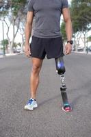 Ritaglia sportivo con gamba protesi in piedi su strada foto