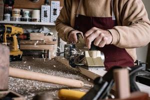 carpentiere che lavora il legno con una spazzola elettrica foto