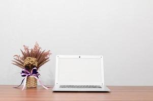 computer portatile e vaso di fiori sulla scrivania