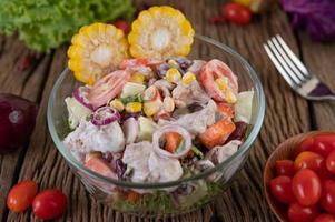 insalata di frutta e verdura in una ciotola di vetro sul tavolo di legno foto