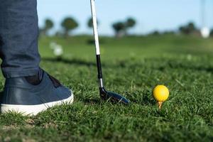 primo piano di scarpe, mazza da golf e pallina da golf su un campo pratica foto