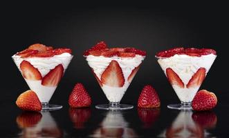 fragole con panna in tazza su sfondo nero foto