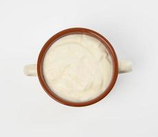 acida crema nel un' Marrone ceramica ciotola su un' bianca sfondo, fermentato latte Prodotto foto