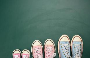 molti multicolore ben indossato tessile scarpe da ginnastica di diverso dimensioni su un' verde sfondo, superiore Visualizza, concetto famiglia foto