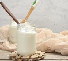 fatti in casa Yogurt nel un' bicchiere trasparente vaso su un' di legno tavolo foto