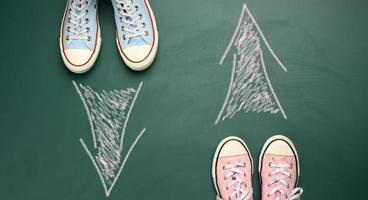 Due coppie di tessile scarpe da ginnastica In piedi di fronte ogni altro su un' verde sfondo foto