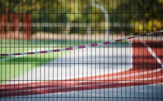 rosso e bianca proibitivo nastro su il recinto di il gli sport complesso. chiuso per visitare, quarantena foto