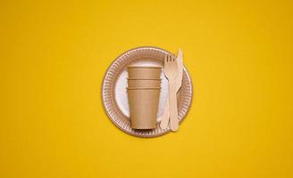 Marrone carta tazze e piatti su un' giallo sfondo. riciclabile spazzatura, rifiuto di plastica, superiore Visualizza foto