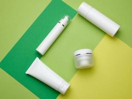 barattolo, bottiglia e vuoto bianca plastica tubi per cosmetici su un' verde sfondo. confezione per crema, gel, siero, pubblicità e Prodotto promozione foto