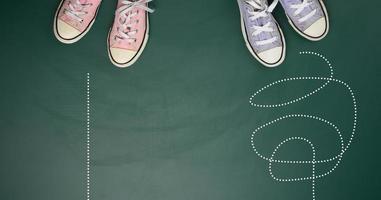 Due coppie di tessile scarpe da ginnastica su un' verde sfondo. il concetto di la scelta un' sentiero è difficile e confuso o dritto e facile foto