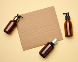 vuoto Marrone foglio di ondulato carta e Marrone bicchiere bottiglie con distributore beige sfondo. confezione per gel, siero, pubblicità e promozione. naturale biologico prodotti. foto