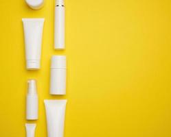 barattolo, bottiglia e vuoto bianca plastica tubi per cosmetici su un' giallo sfondo. confezione per crema, gel, siero, pubblicità e Prodotto promozione, finto su foto