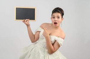 giovane asiatico bellissimo sposa posa con vuoto lavagna nel mano foto