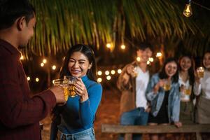 ritratto di contento asiatico amici avendo cena festa insieme - giovane persone tostatura birra bicchieri cena all'aperto - le persone, cibo, bevanda stile di vita, nuovo anno celebrazione concetto. foto