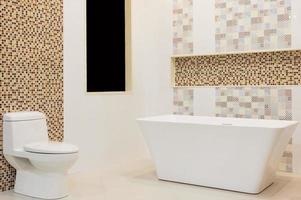 interno del bagno bianco di lusso con piastrelle bianche, specchio, un lavandino e una vasca da bagno bianca. concetto di relax. foto