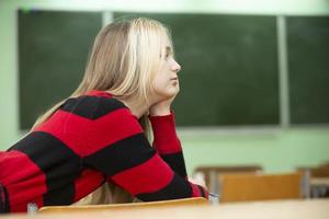 un' adolescenziale ragazza bugie su un' scuola scrivania. alto scuola alunno. quindici anno vecchio ragazza. foto