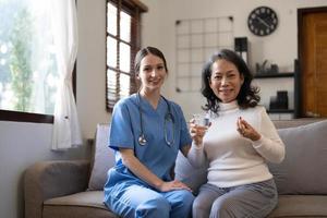 asiatico infermiera mostrando Salute verifica rapporto per nonna e dando consiglio. medico Assistito vivente visitare anziano paziente a casa. casa assistenza infermieristica e assistenza sanitaria badante concetto foto