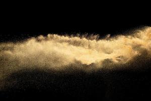 spruzzata di sabbia di colore marrone. esplosione di sabbia di fiume secca isolata su sfondo nero. foto