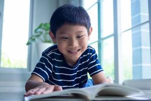 il poco ragazzo è lettura un' libro nel il Casa la zona. apprendimento a casa foto