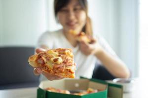 Affamato donna gode mangiare hawaiano Pizza dopo ordine in linea per mangiare a casa. contento e rilassato per mangiare concetto foto