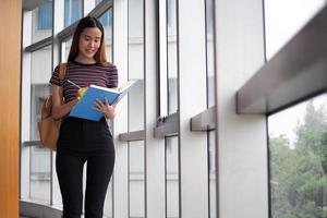 asiatico studenti In piedi lettura libri nel il Università biblioteca. foto