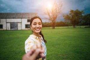 donna che cammina e tiene la mano del fidanzato che la segue foto