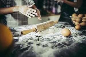 piccolo chef che usa il mattarello per stendere la pasta foto