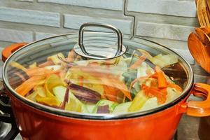 pezzi di tricolore carote siamo cucinato nel casseruola su gas stufa foto