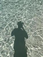 estate vibrazione, spiaggia con silhouette di un' donna riflettendo su acqua superficie, sfondo con copia spazio, silhouette di le persone, persone ombre con riflessione su il mare, estate primavera natura foto
