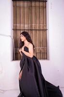 triste asiatico donna in piedi nel davanti di il Marrone di legno finestra mentre indossare un' nero vestito foto