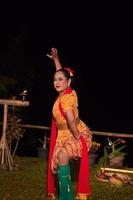 asiatico donna l'esecuzione un' tradizionale danza chiamato jaipong nel Indonesia con un' giallo vestito e rosso sciarpa foto