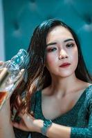 asiatico donne con blu vestiti bevanda vino dritto a partire dal il bottiglia mentre partying foto