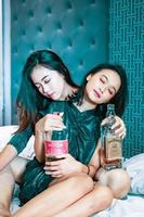 asiatico donne Tenere un alcool bottiglia nel loro mano nel il Camera da letto foto