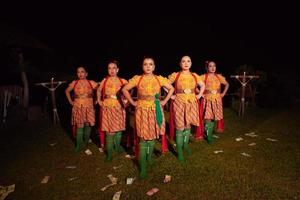 balinese ballerini in piedi insieme con rosso sciarpa e arancia costumi su il palcoscenico dopo l'esecuzione il tradizionale danza foto