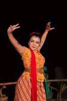 balinese donna nel tradizionale arancia vestito danza con un' rosso sciarpa mentre l'esecuzione danza foto