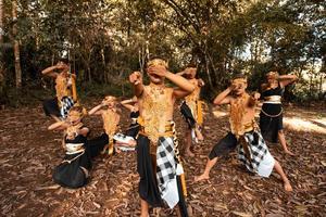 balinese ballerini con d'oro costumi e nudo pantaloni danza insieme con il morto Marrone le foglie nel il cortile foto