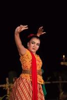 balinese donna nel tradizionale arancia vestito danza con un' rosso sciarpa mentre l'esecuzione danza foto