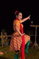 asiatico donna l'esecuzione un' tradizionale danza chiamato jaipong nel Indonesia con un' giallo vestito e rosso sciarpa foto