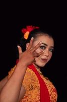 acuto occhi a partire dal indonesiano donne con trucco mentre indossare un arancia vestito a il danza Festival foto