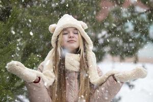 un' bellissimo ragazza nel un' pelliccia cappello e guanti catture fiocchi di neve. adolescenziale ragazza nel inverno. nevoso tempo atmosferico. foto