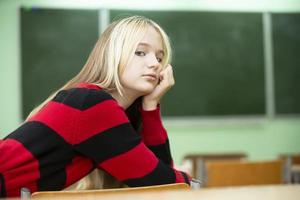 un' adolescenziale ragazza bugie su un' scuola scrivania. alto scuola alunno. quindici anno vecchio ragazza. foto