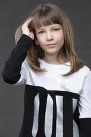 bellissimo dieci anno vecchio ragazza su un' grigio sfondo. foto
