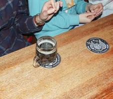 slovacchia, Bratislava - 01.07.2023 boccale di birra su un' di legno tavolo. mani di persone seduta a il tavolo. foto