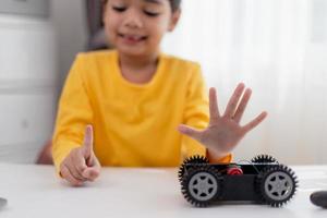 gli studenti asiatici imparano a casa a codificare auto robot e cavi di schede elettroniche in stelo, vapore, matematica ingegneria scienza tecnologia codice informatico in robotica per bambini concetto. foto