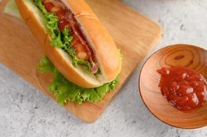 hot dog con lattuga e pomodoro su un tagliere di legno foto