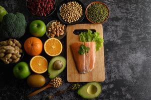 legumi, frutta e salmone su un tagliere di legno foto