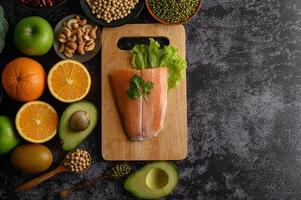 legumi, frutta e salmone su un tagliere di legno foto